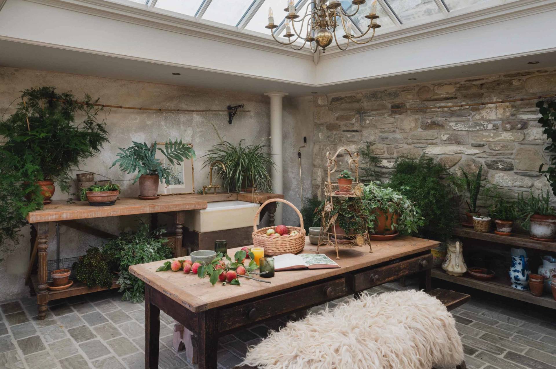 Rustic glasshouse dining venue filled with potted plants and natural sunlight in a Cornish manor by Love Locations.