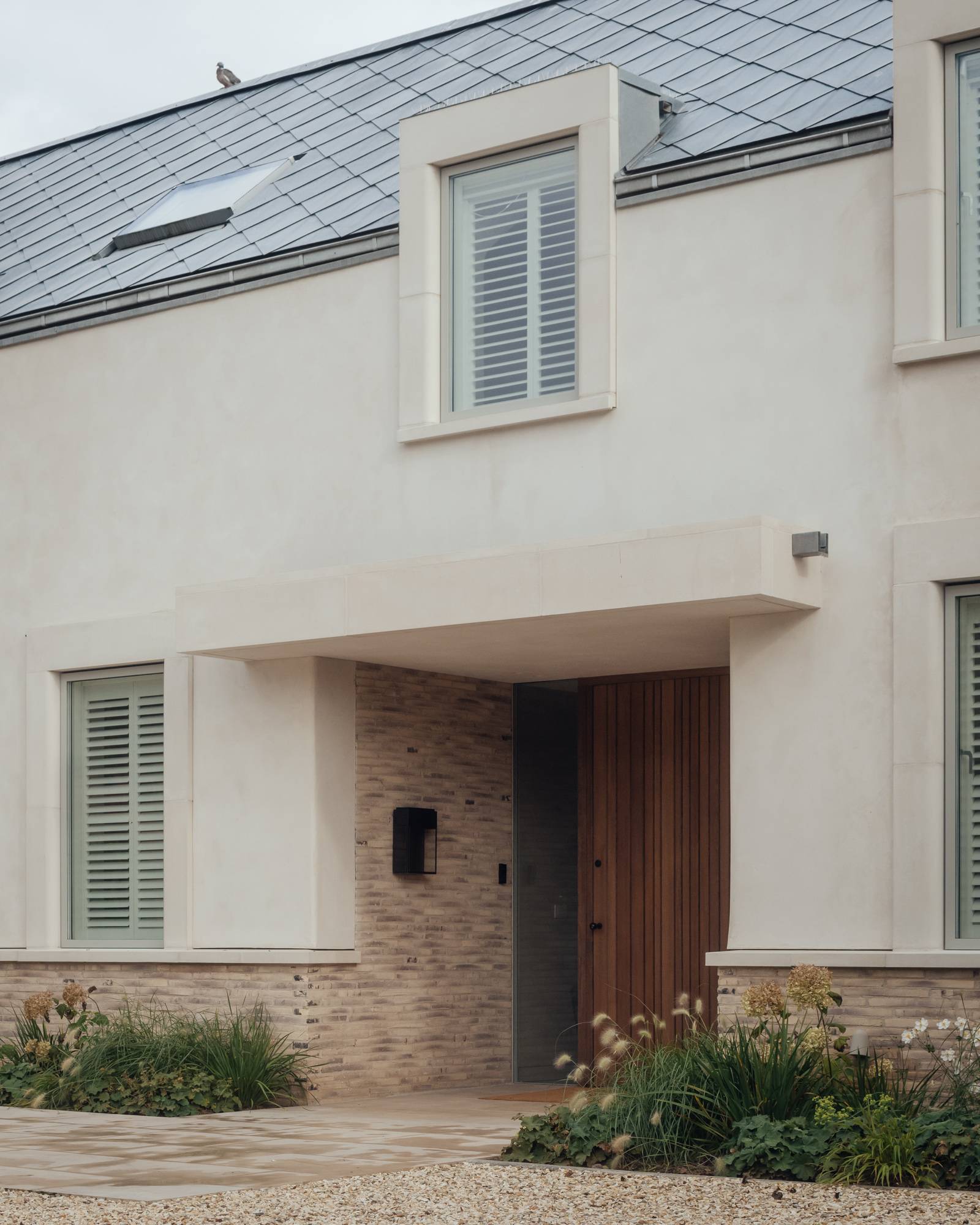 Close-up of a modern front entrance porch featuring a solid timber front door and stone brick plinth details, Love Locations SO20.