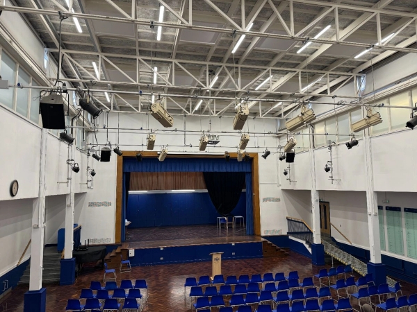 Love Locations institutional hall shoot space Cockfosters: High-angle view of a secondary school presentation hall with overhead production lighting, tailored for television series and drama background scenes.