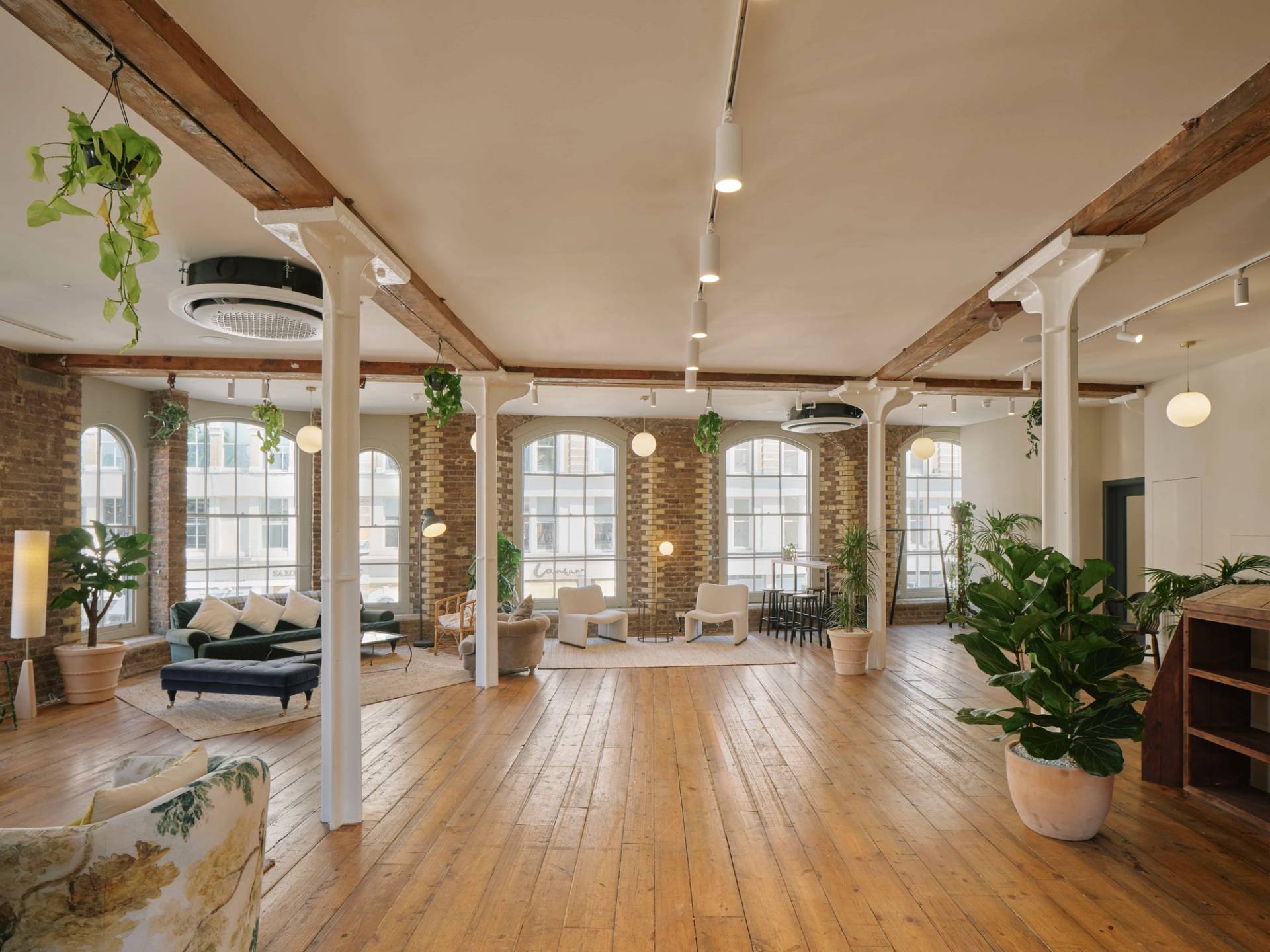 seating area by the large arched windows, with soft furnishings, plants, and warm sunlight.