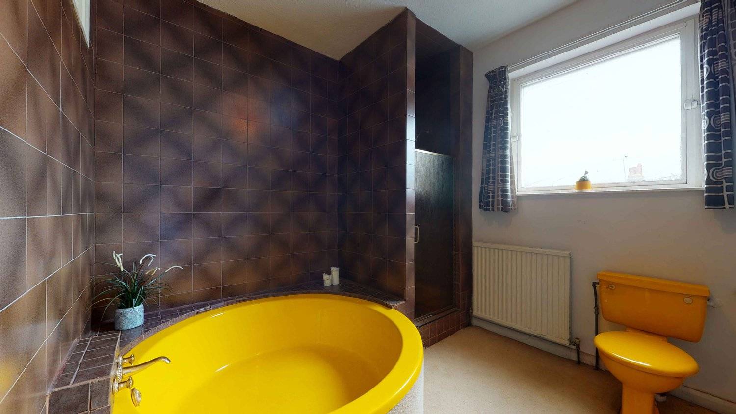 Authentic 1970s bathroom featuring a sunken circular bright yellow bathtub, dark patterned wall tiles, and retro fixtures, Love Locations SW16.