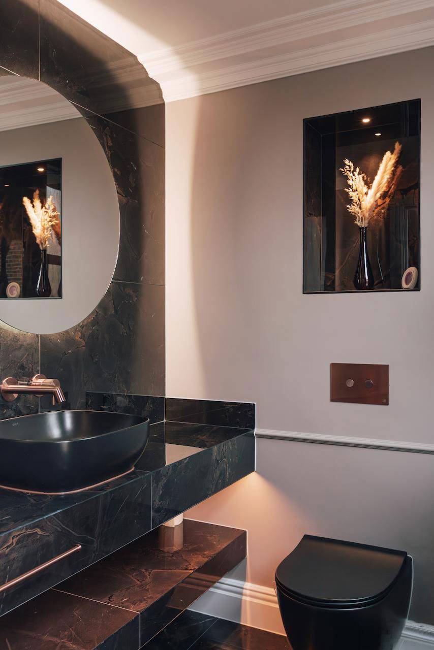 Atmospheric powder room featuring a dark marble basin vanity and backlit round mirror, ideal for grooming product marketing, Love Locations W5.