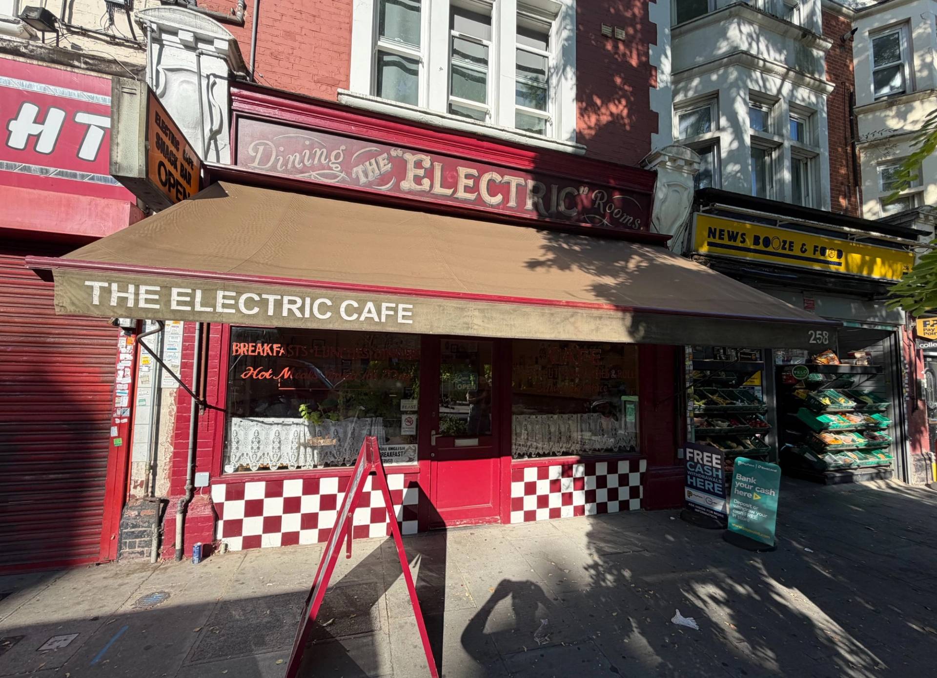 Classic red facade cafe exterior with retractable awning, storefront signage, and A-board chalkboard, Love Locations SE27.