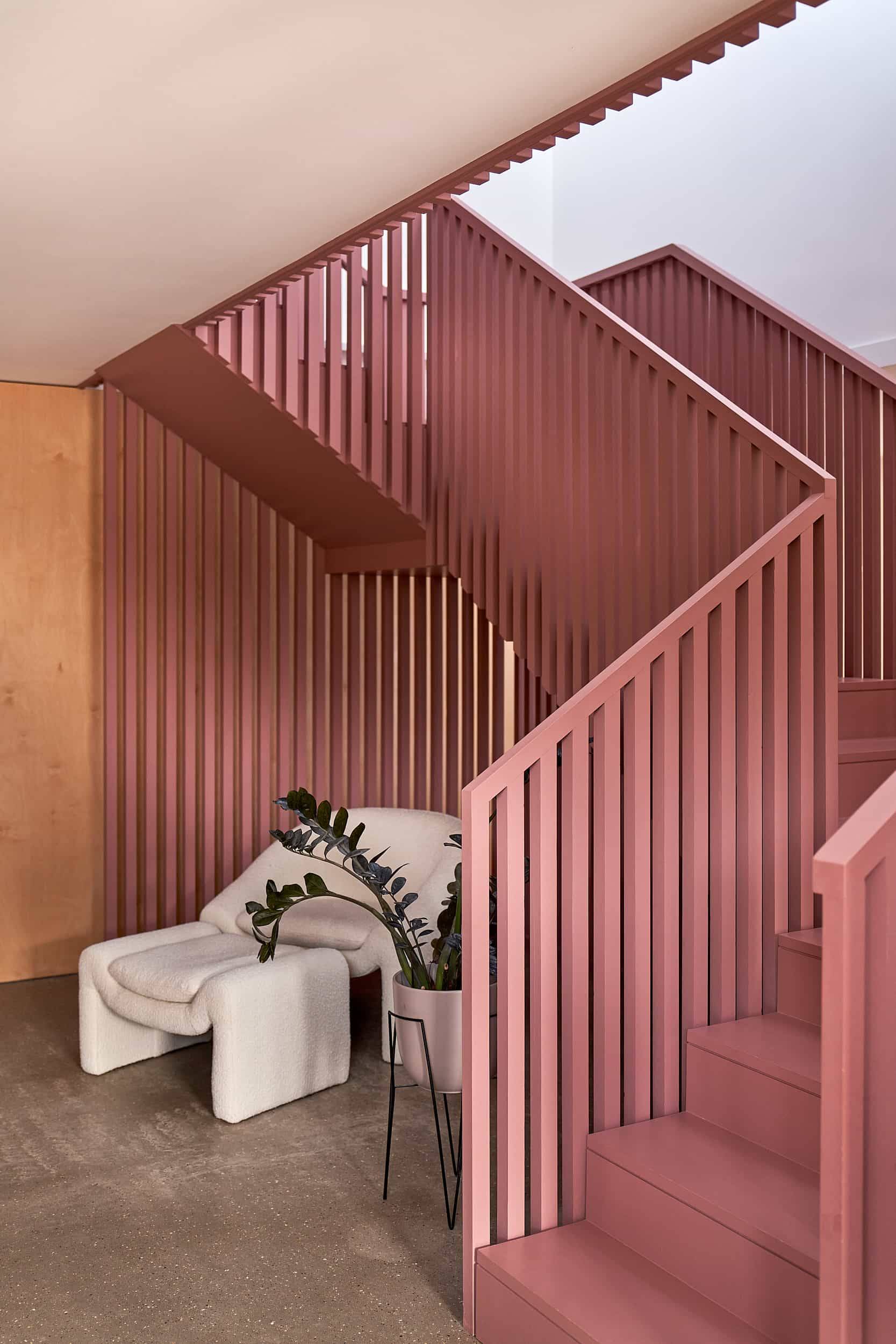 Terracotta pink slatted staircase feature wall set on polished concrete floors with a white bouclé lounge chair, Love Locations IP30.