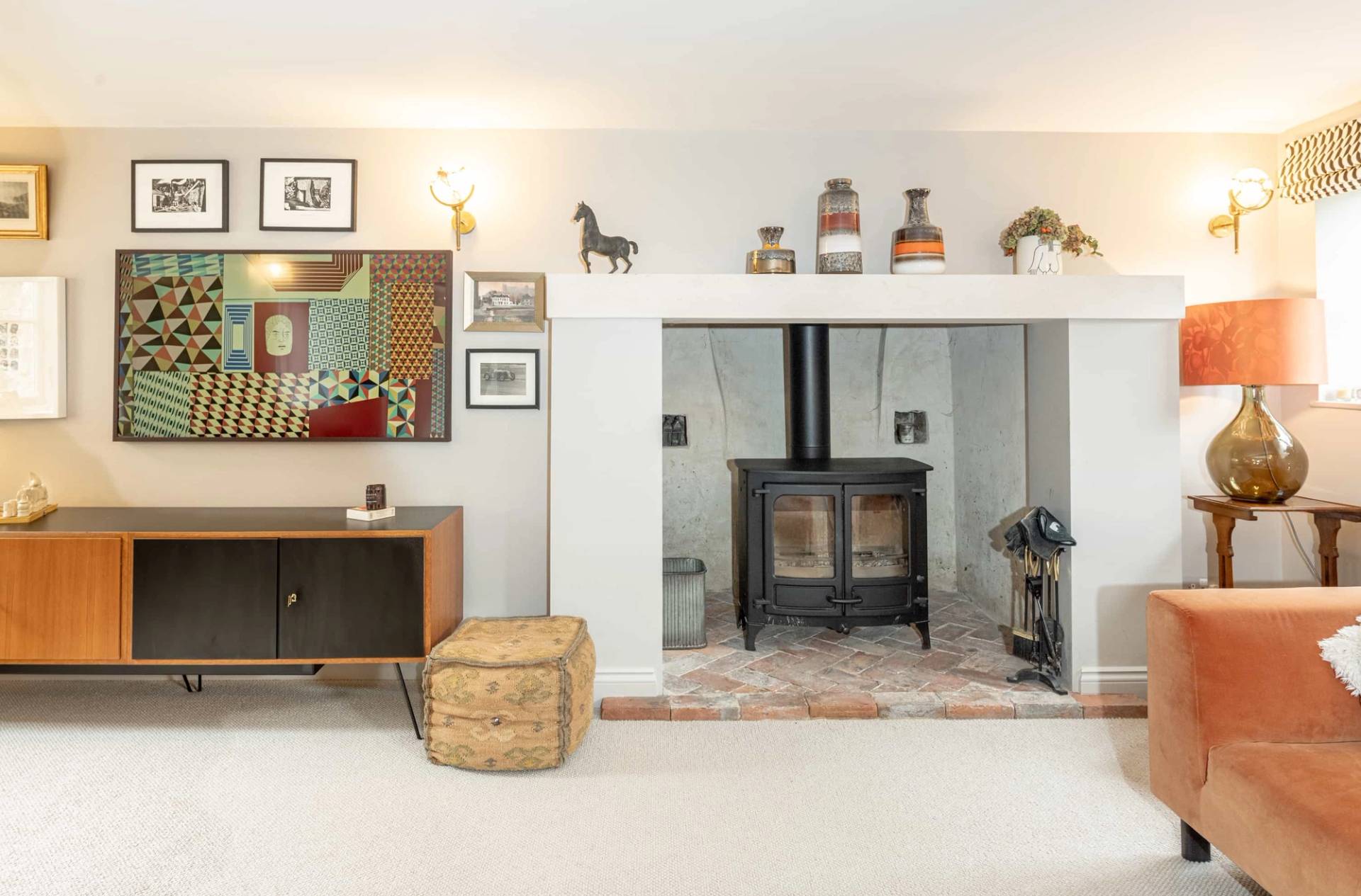 Recessed inglenook fireplace with a dark wood-burning stove and log basket set on white floor tiles, Love Locations GU28.