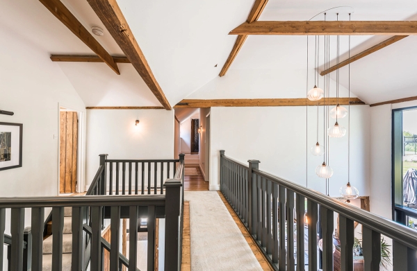 Elevated interior mezzanine gallery balcony with exposed roof trusses inside a converted barn in Chelmsford, Love Locations CM3.