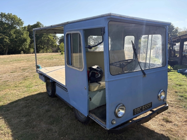Vintage blue electric flatbed utility truck parked in a rural field location, Love Locations BN8.