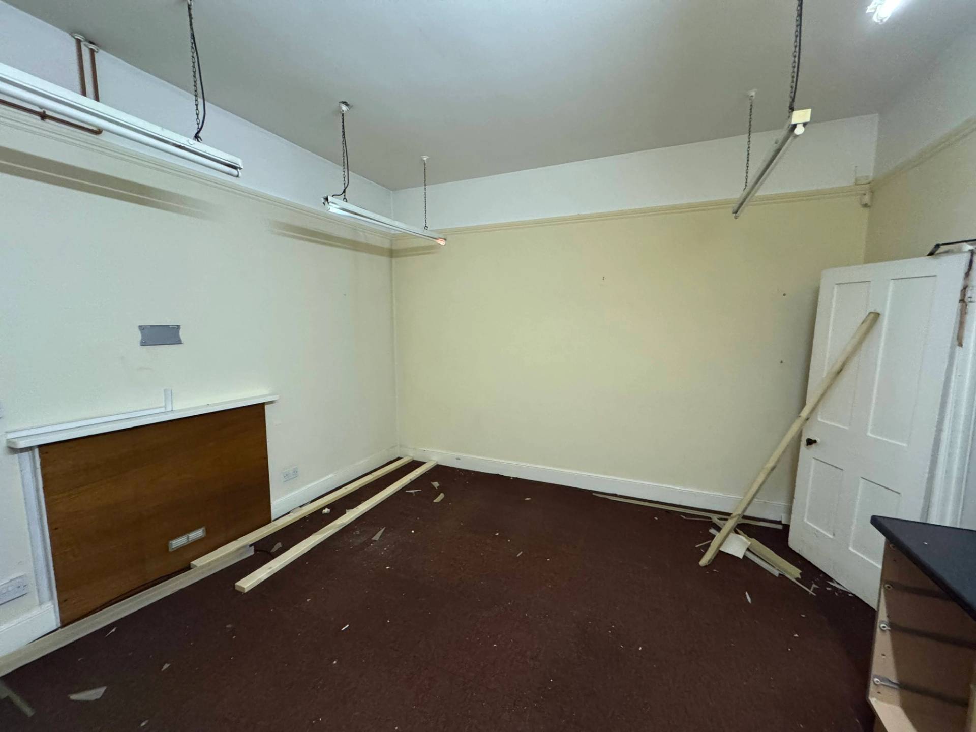 Distressed interior room featuring loose timber framework on the floor and fluorescent strip lights, listed on Love Locations.