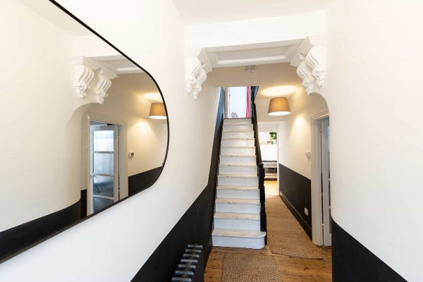 Love Locations grand entrance hall Forest Gate East London: Period hallway featuring white corbel arches, a large oval mirror, and a bold black-and-white painted color split, perfect for fashion lookbooks.
