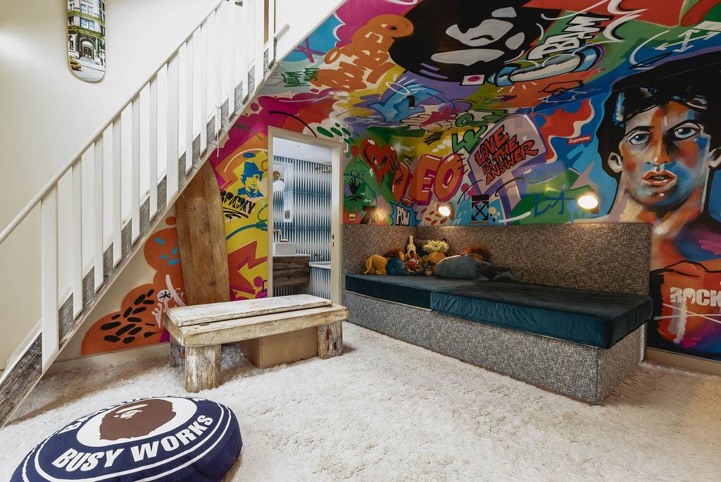 Bedroom with a vibrant street art graffiti wall, wooden bench, and bean bag, Love Locations GU32.