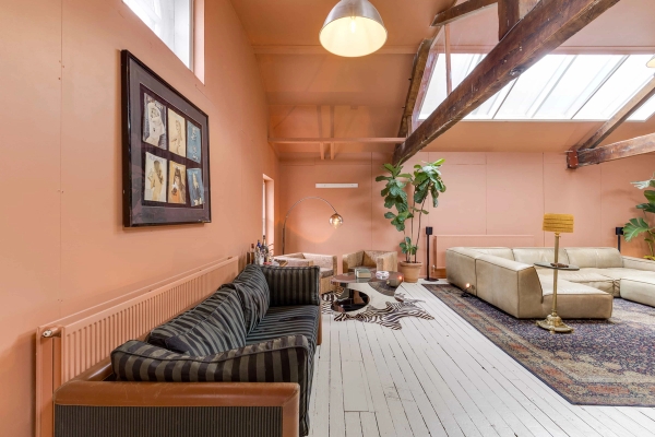 Spacious loft studio apartment featuring exposed timber roof trusses and unique pink wall tones, booked via Love Locations.