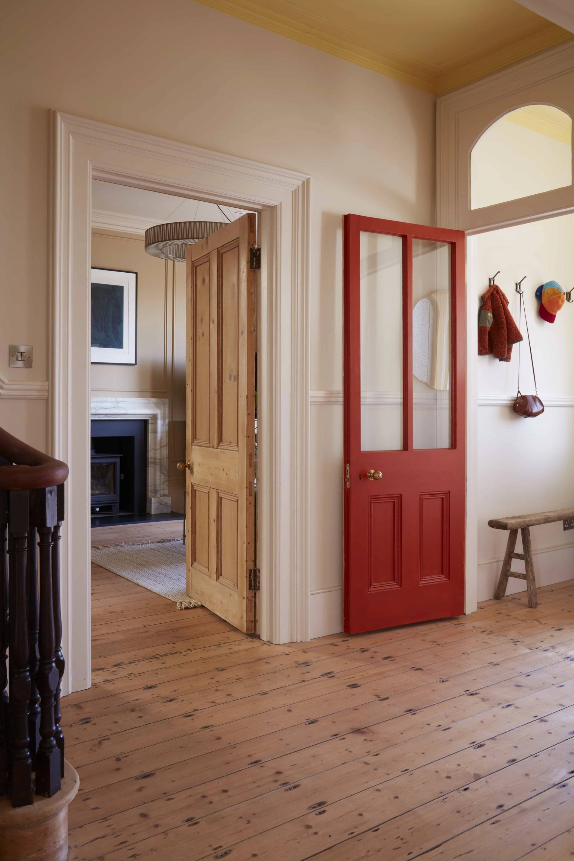 Hallway view looking through an open red painted door into a period reception room, Love Locations.