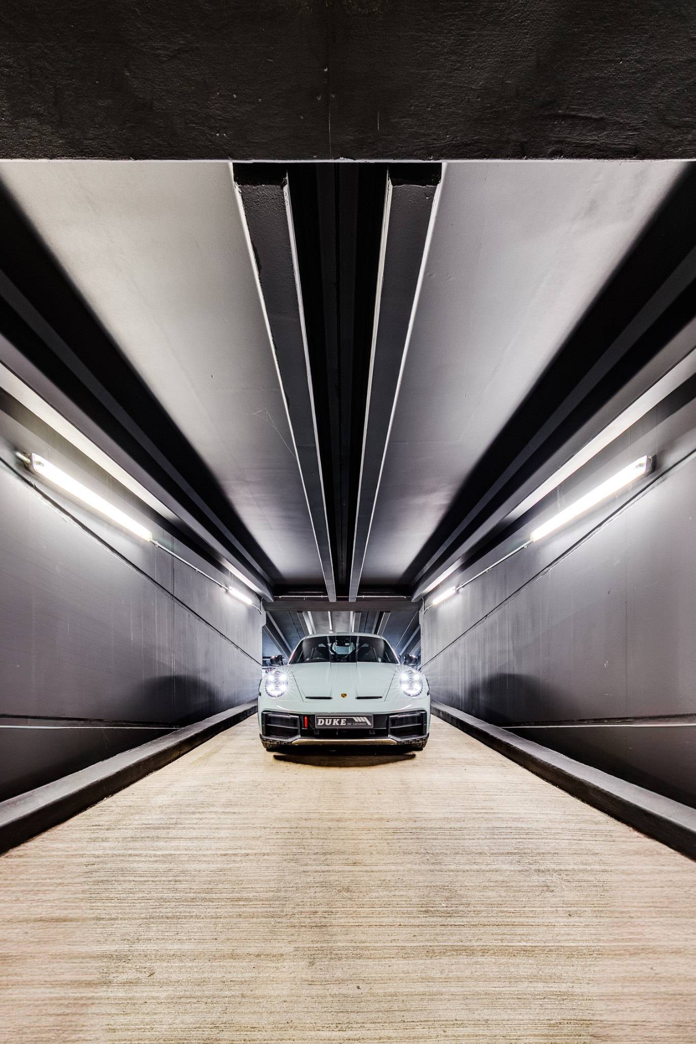Frontal view of a grey Porsche sports car in a modern dark car studio in Brentford TW8 via Love Locations.