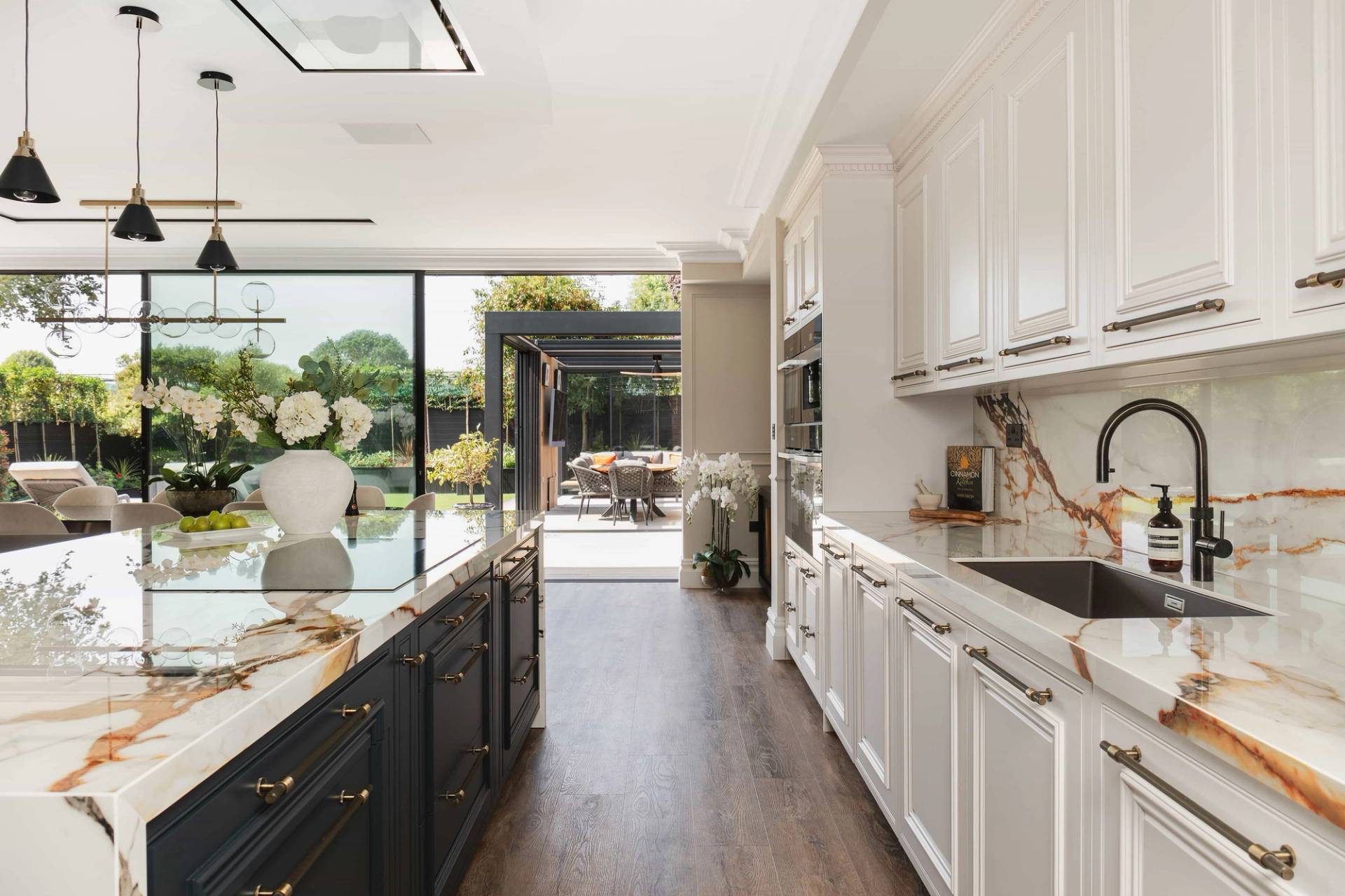 Sleek kitchen view looking out through open sliding glass doors onto an outdoor pergola patio, ideal for indoor-outdoor lifestyle shoots, Love Locations.