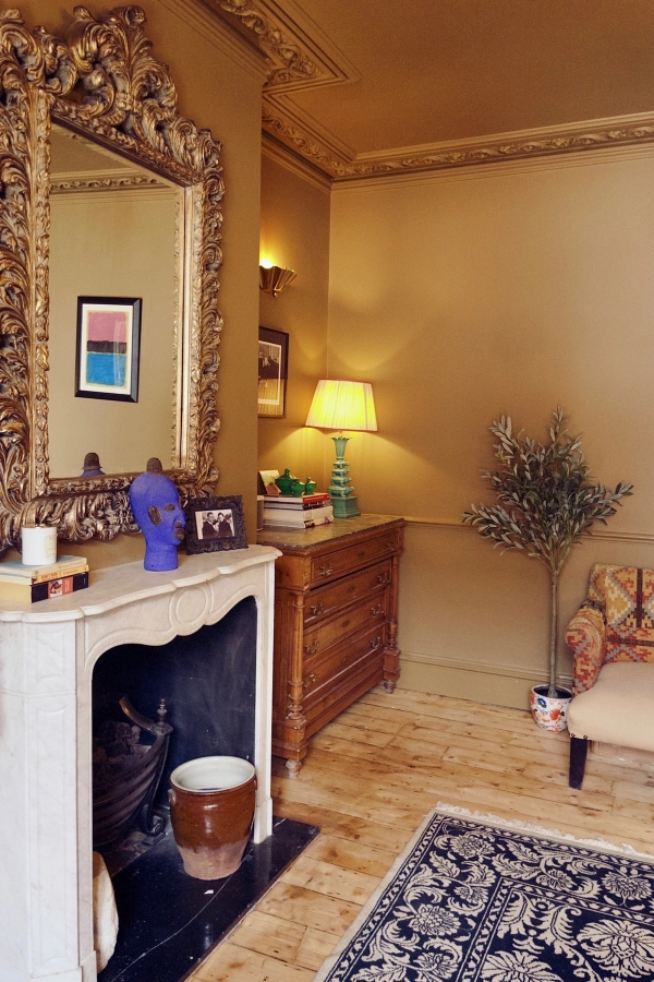 Chic eclectic living room location featuring a traditional fireplace mantel, antique cabinet, and decorative mirror in Isleworth, West London, ideal for period drama scenes via Love Locations.
