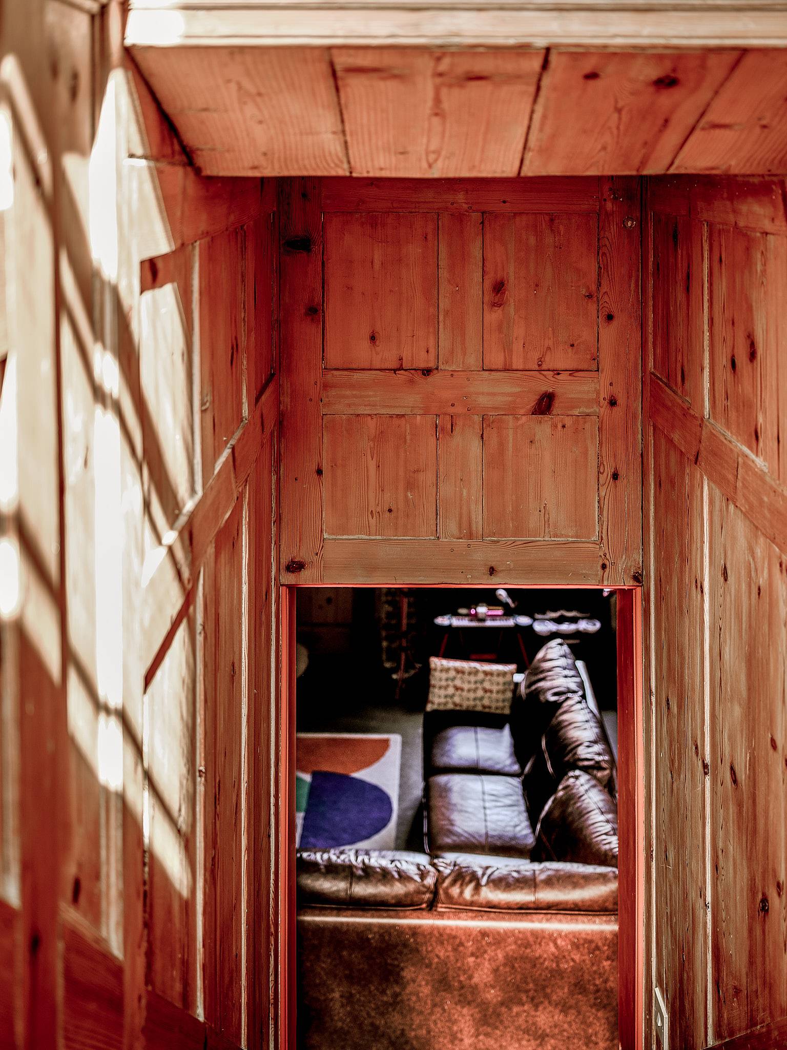 High-angle perspective looking down a timber panelled stairwell onto a leather sofa below, Love Locations.