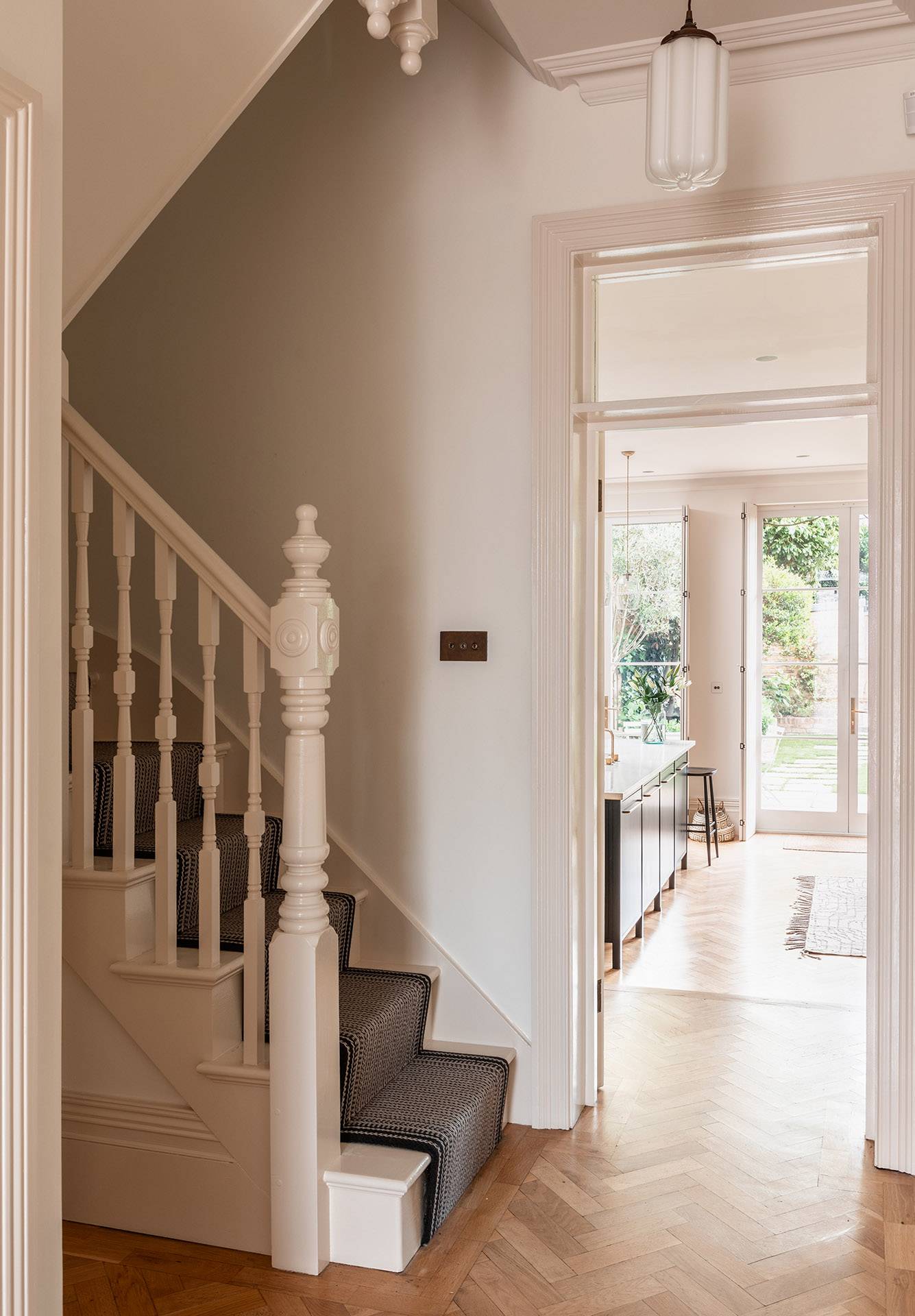 Bright hallway stairwell with a white carved wooden balustrade and neutral runner carpet, perfect for domestic brand filming, Love Locations.