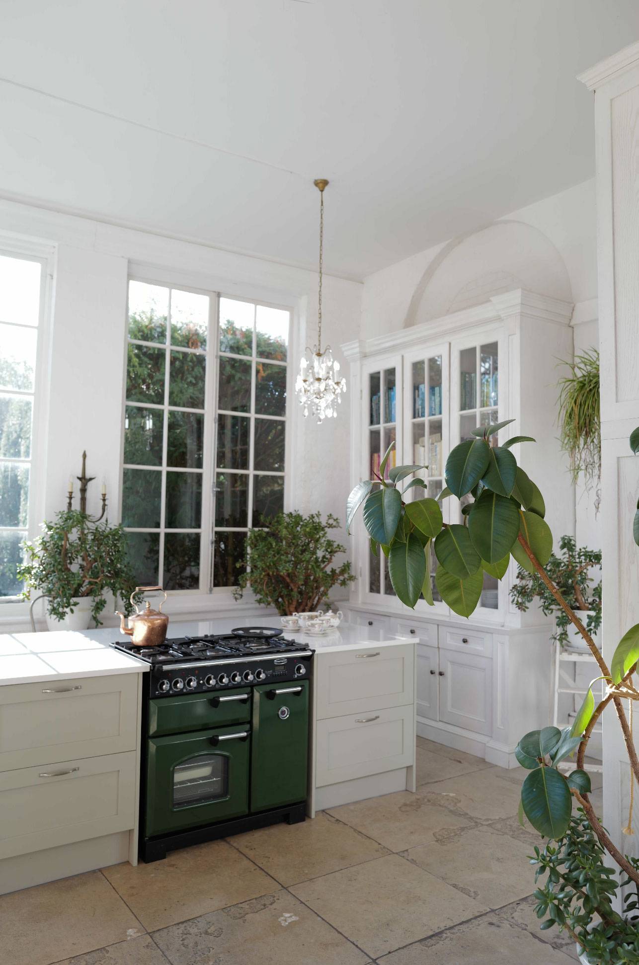 Traditional country kitchen prep space with a green Range oven, marble countertops, and potted houseplants, Love Locations RG42.