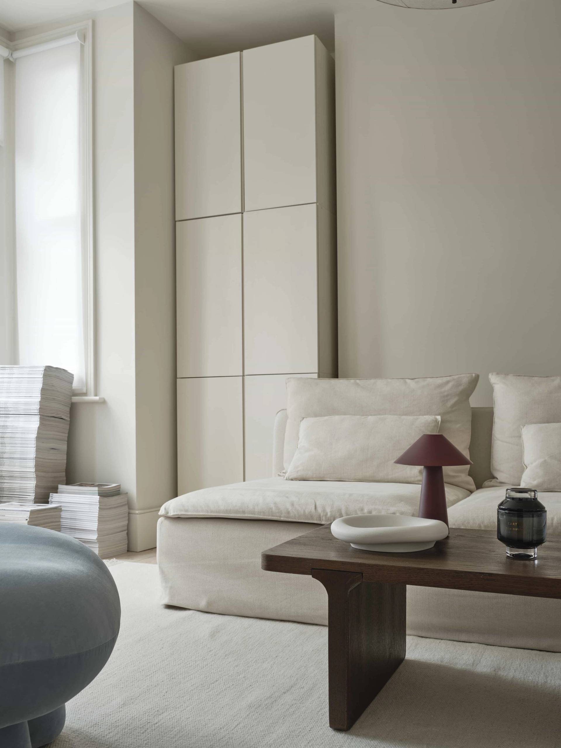 Close-up of a low-profile cream sofa and dark timber coffee table styled with a portable mushroom lamp, Love Locations E4.