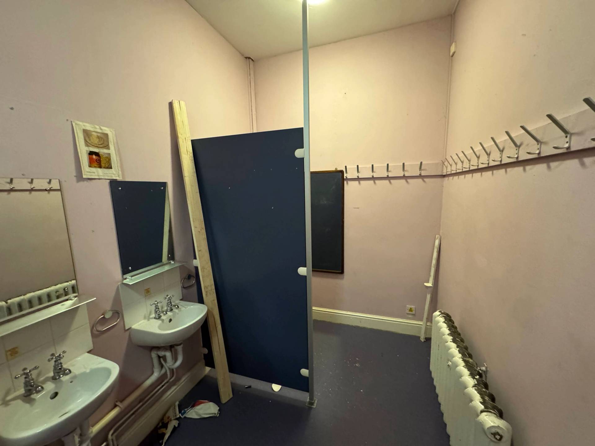 Institutional bathroom facility showing blue laminate privacy cubicle panels and industrial flooring, Love Locations.