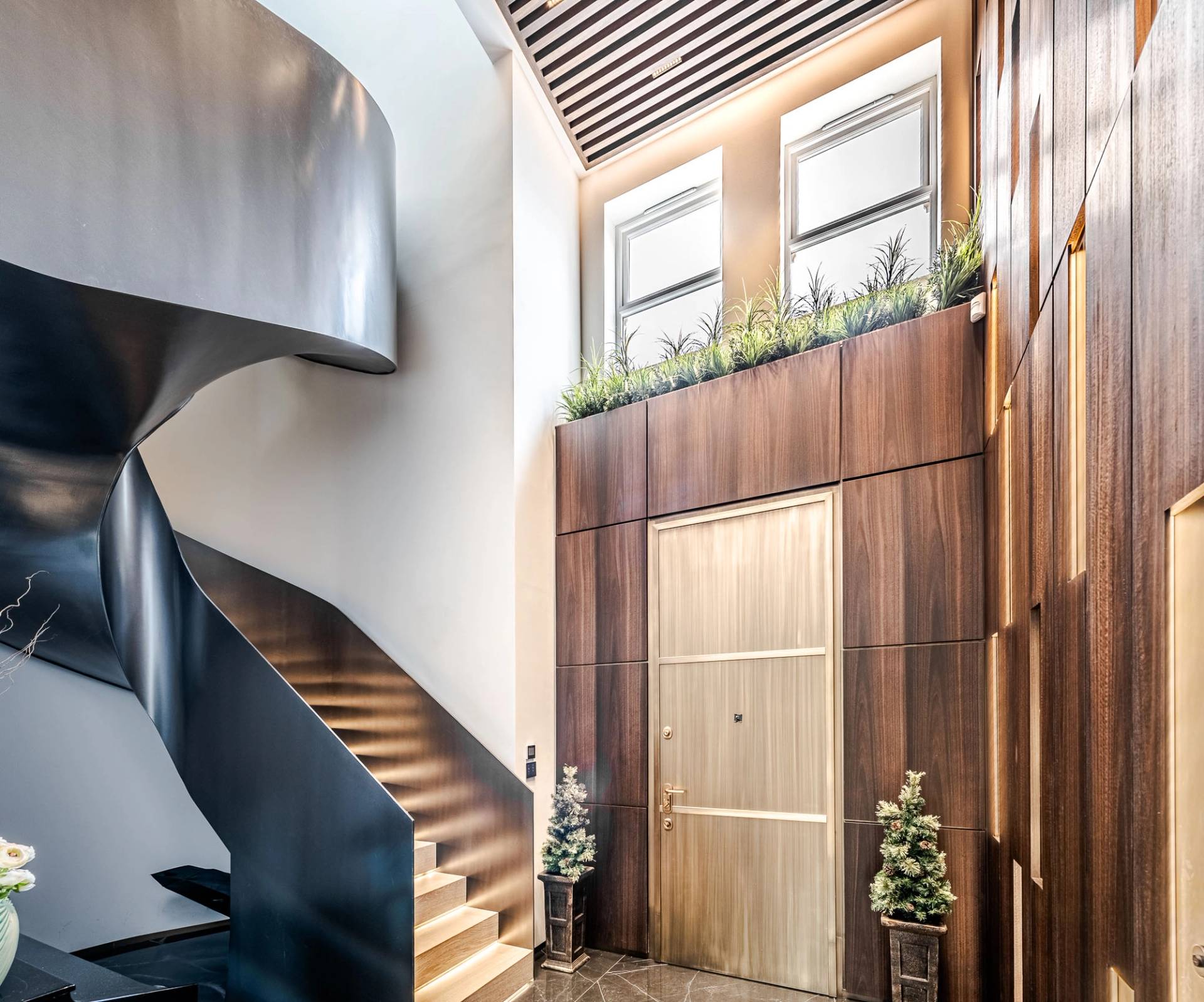 Sculptural dark metal helical staircase with timber treads set under a glass sky roof, Love Locations SW11.