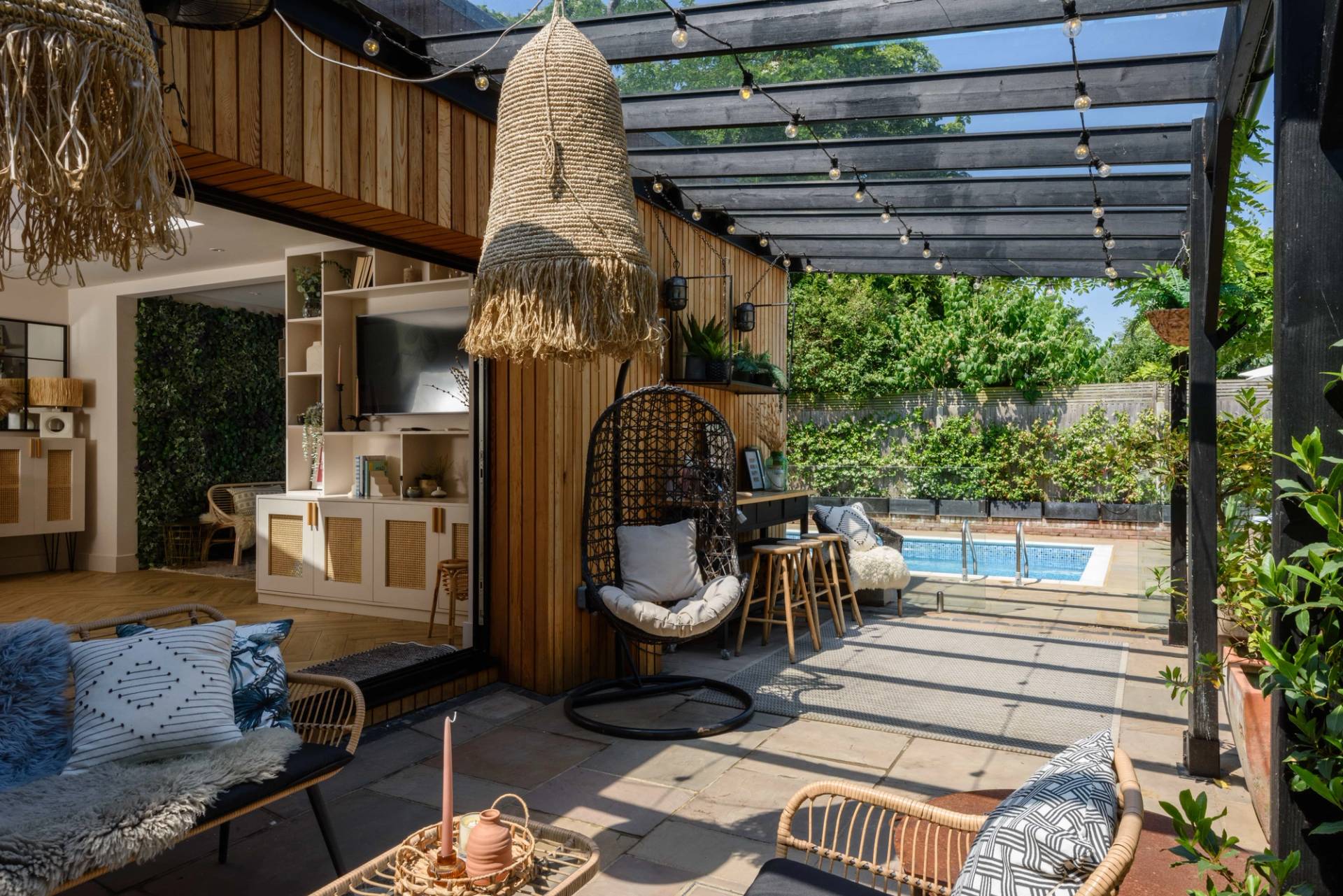 Shaded garden pergola terrace with hanging wicker chairs, timber decking, and glass roof, Love Locations TW11.