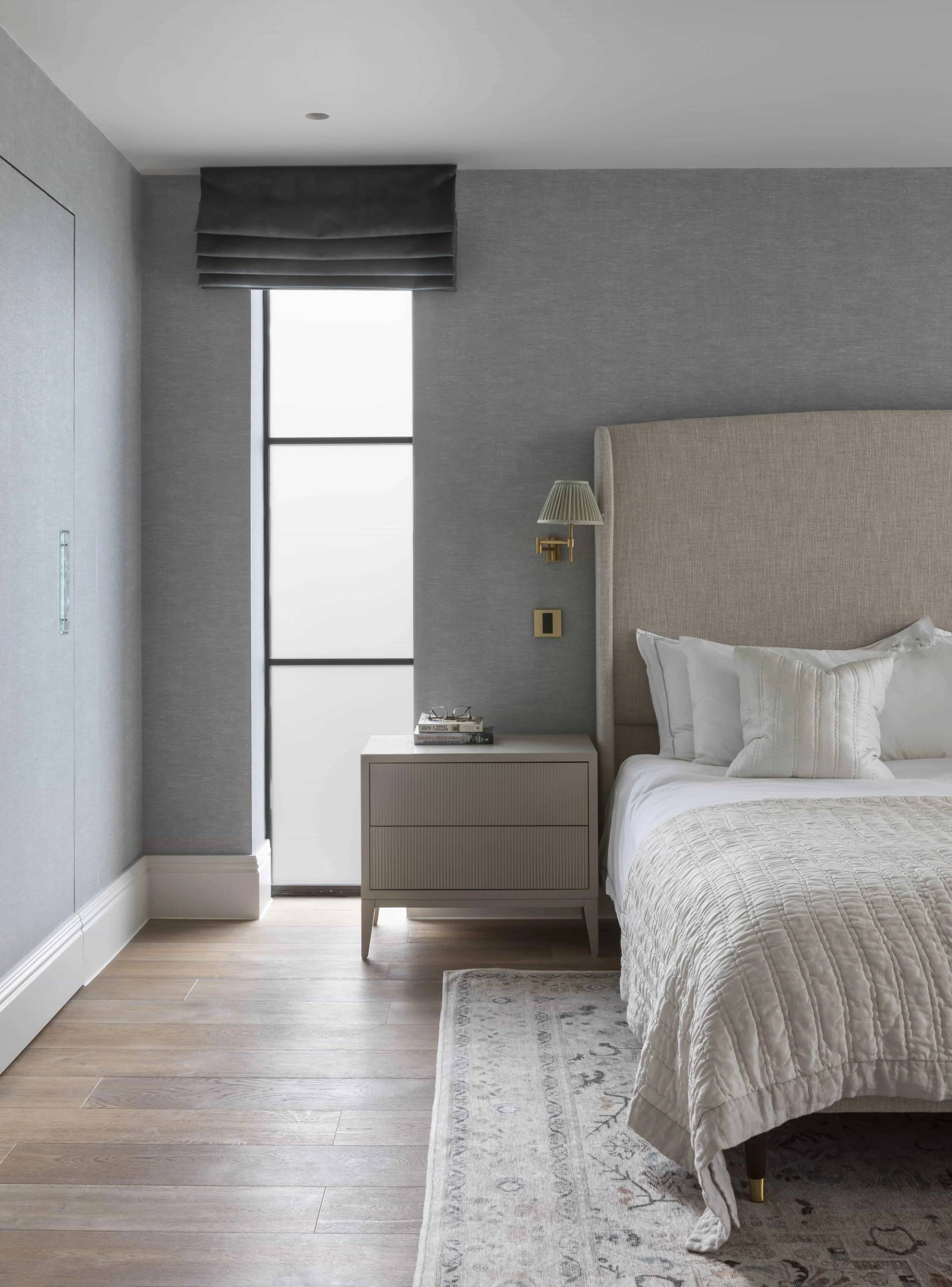 Master bedroom corner showing a tall beige headboard, grey window blinds, and dark wood floors, Love Locations HP18.