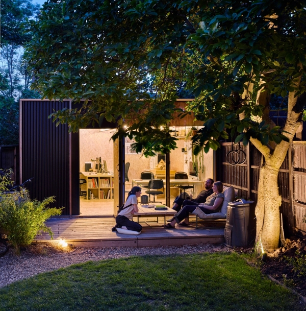 Cozy garden studio outbuilding illuminated at dusk with deck seating in Walthamstow, Love Locations E17.