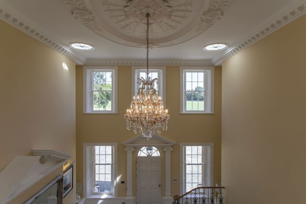 Symmetric double-height Georgian sash windows and luxury crystal chandelier in a country house shoot location, managed by Love Locations.