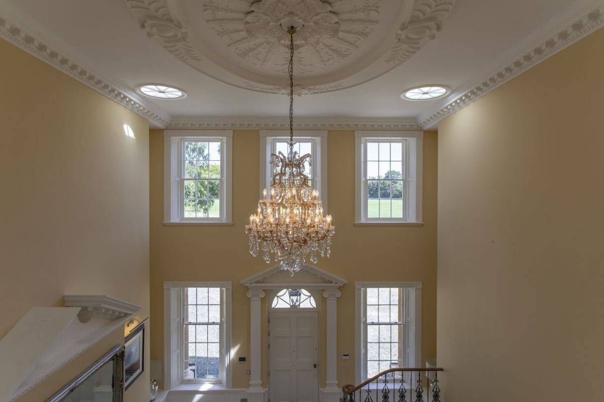 Symmetric double-height Georgian sash windows and luxury crystal chandelier in a country house shoot location, managed by Love Locations.