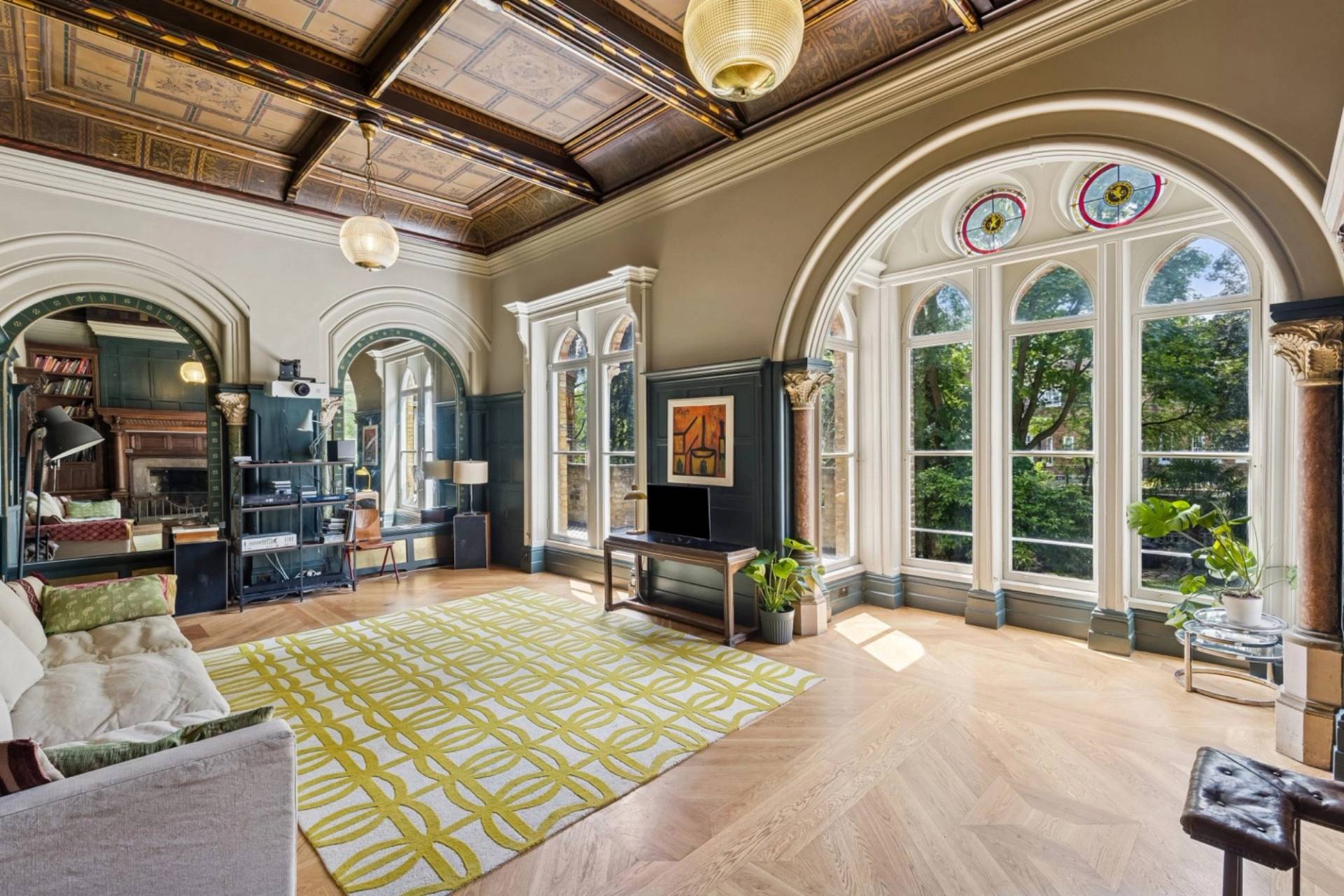 Wide view of a grand library sitting room with parquet flooring and coffered ceiling in Hampstead NW3 through Love Locations.