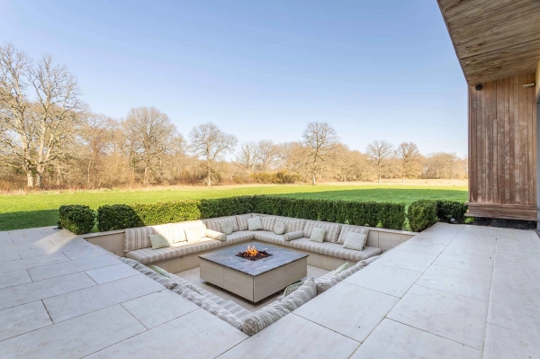 Love Locations unique outdoor feature location GU8: Sunken patio terrace framing wide, unobstructed countryside views beyond pristine lawns, ideal for outdoor lifestyle photography.