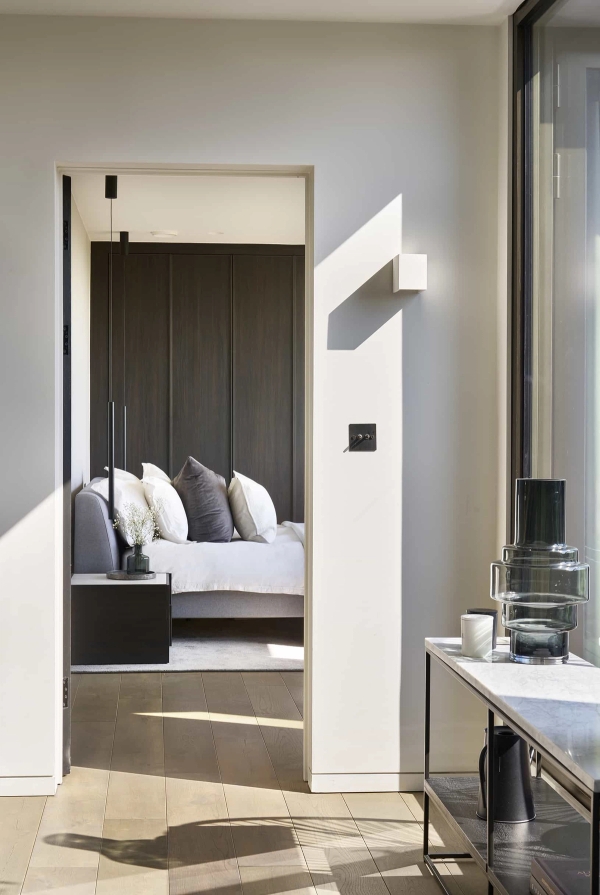 Sleek master bedroom suite entry featuring dark wood accent panels and clean architectural lines, Love Locations.