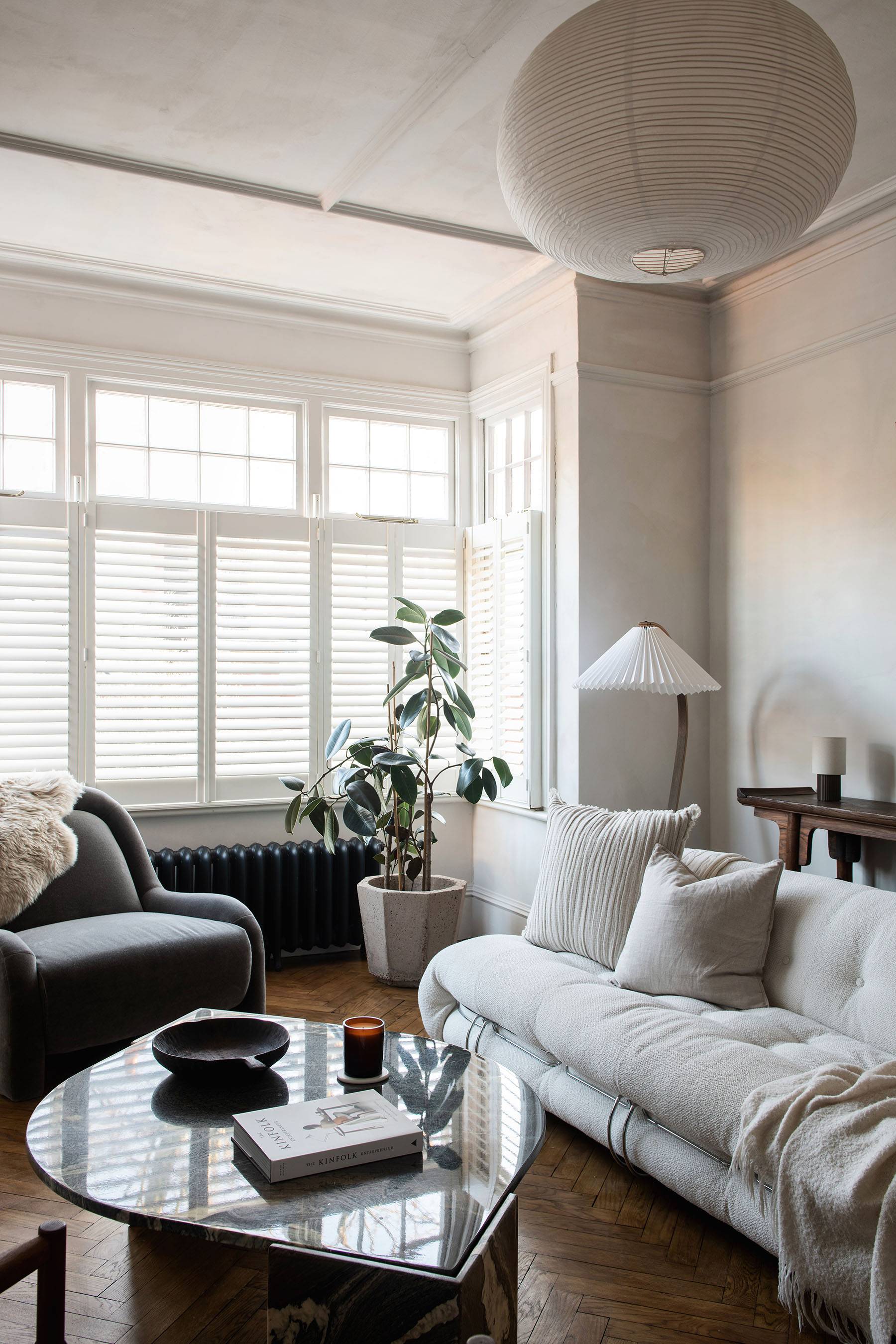 Modern low-profile cream sofa set against raw plaster walls with a minimalist bench and ceramic decor, Love Locations.