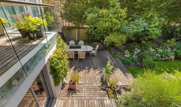 Private terraced wooden garden deck surrounded by dense green shrubbery, ideal for outdoor summer gathering brand campaigns, Love Locations.