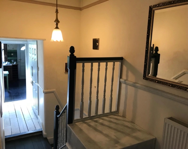 Bright upper-floor stairwell landing showing dark painted railings and warm cream walls in a South London house, Love Locations SE25.
