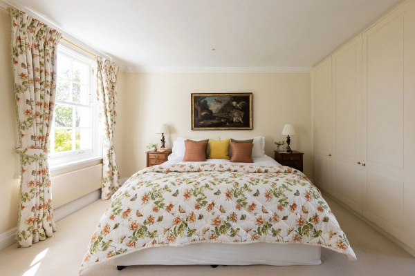 Love Locations traditional English bedroom Ashington BN44: Bright guest suite styled with an ornate floral quilted bedspread and gold-framed art print, ideal for home catalogs and brand ads.