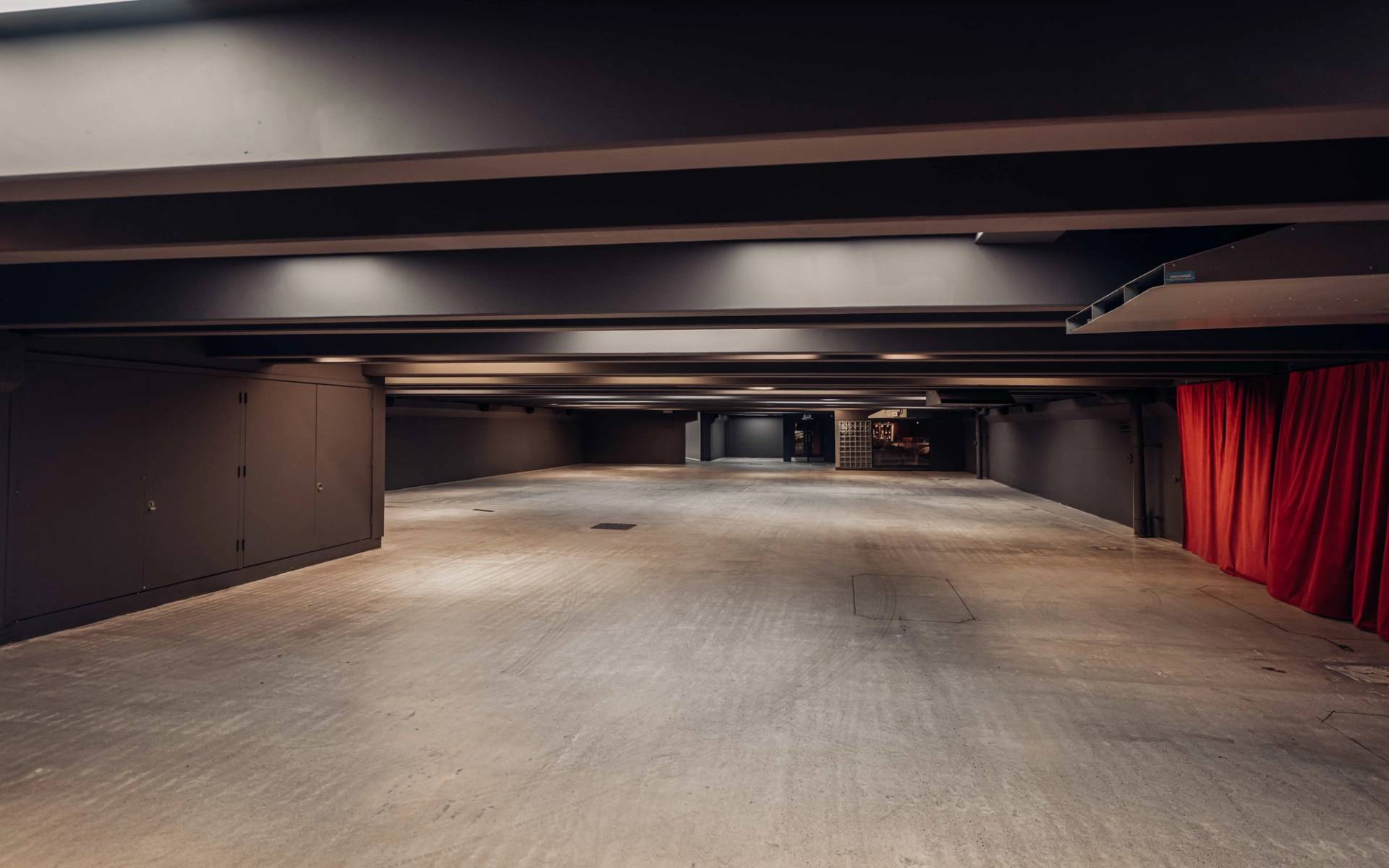 : Sprawling empty underground concrete bunker location house in Brentford TW8 from Love Locations, featuring dark recessed ceilings, concrete flooring, and ambient strip lighting.