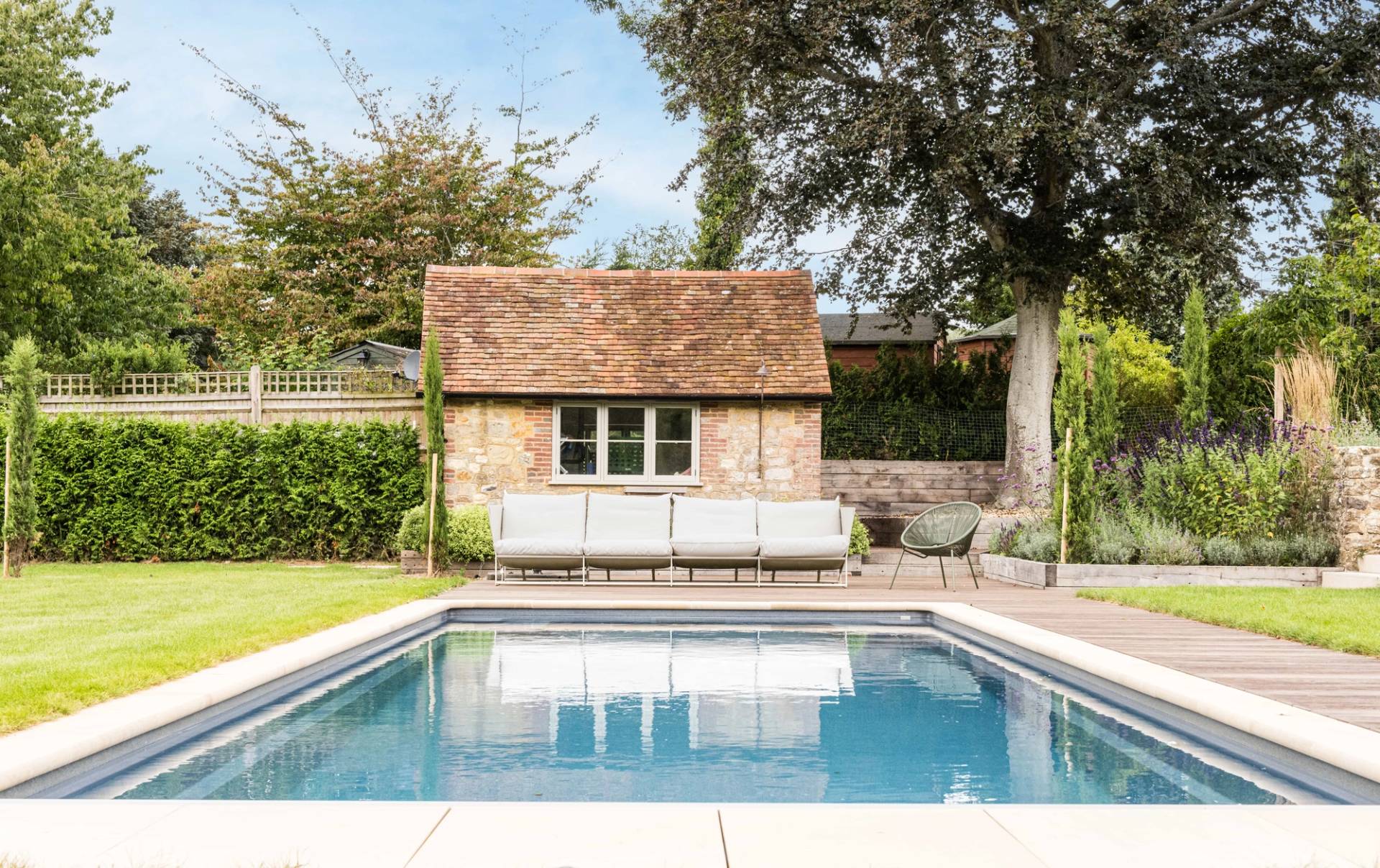 Heated outdoor lap pool set beside a stone pool house pool room on a private West Sussex estate, Love Locations GU28.