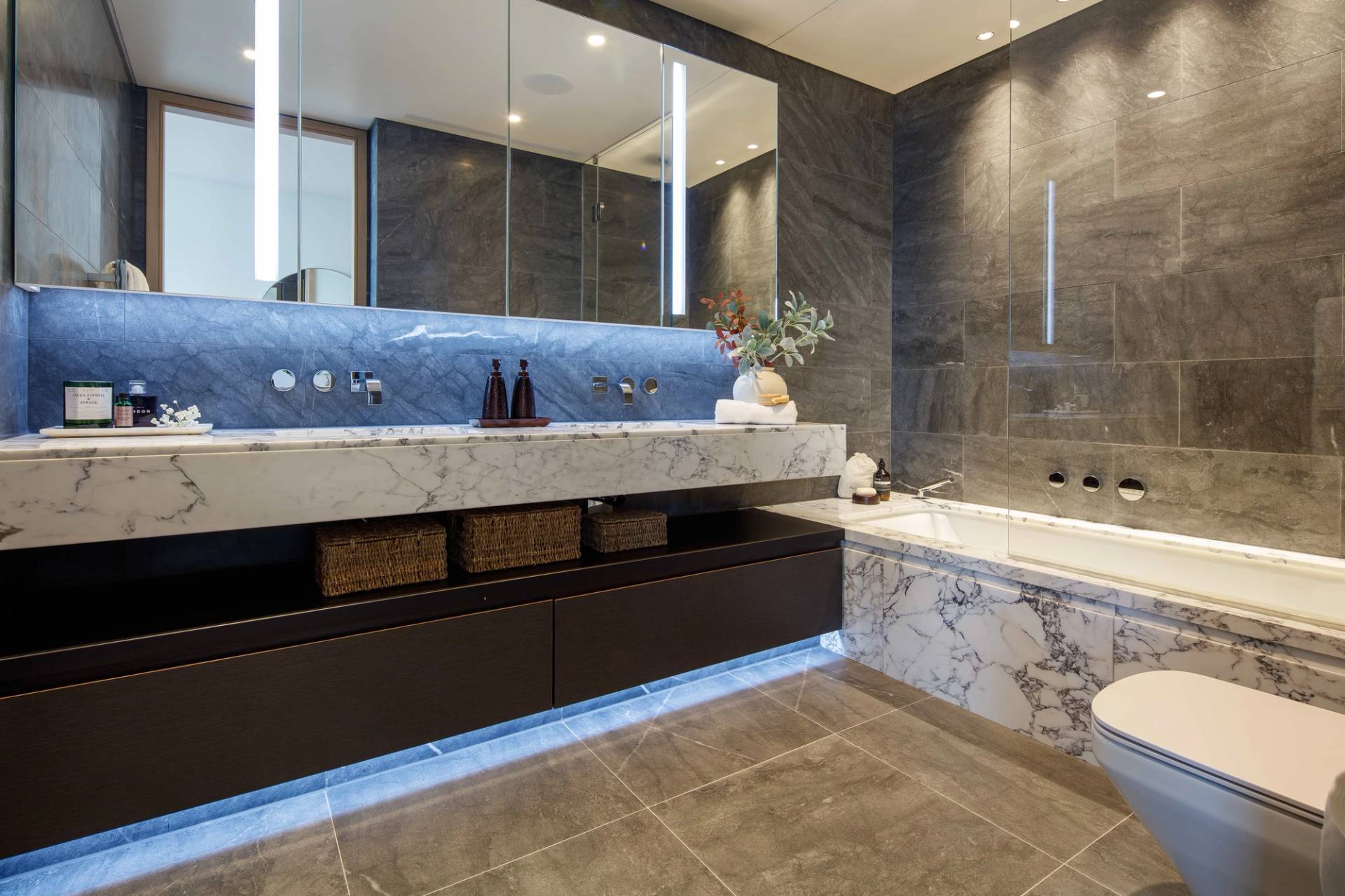 Spacious marble bathroom suite with integrated tub, walk-in glass shower, and ambient strip lighting, perfect for spa and wellness brand shoots, Love Locations.