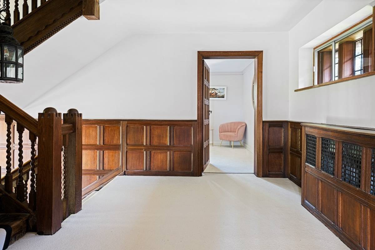 Upper landing corridor with dark oak panelling leading toward light-filled bedroom doors, Love Locations RH13.