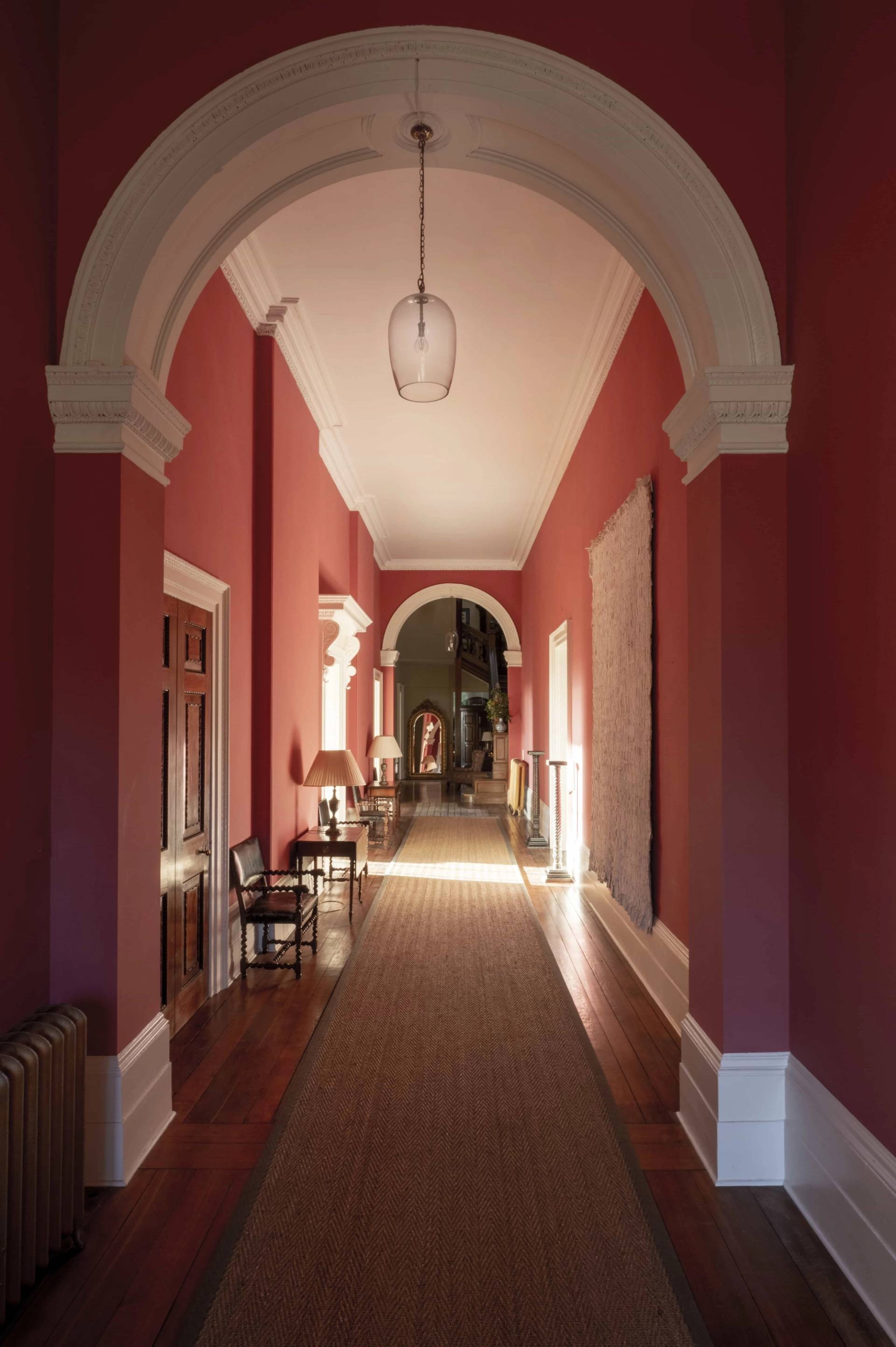 Grand terracotta red arched hallway with dark polished floorboards and runner carpet, perfect for dramatic film establishing shots, Love Locations.