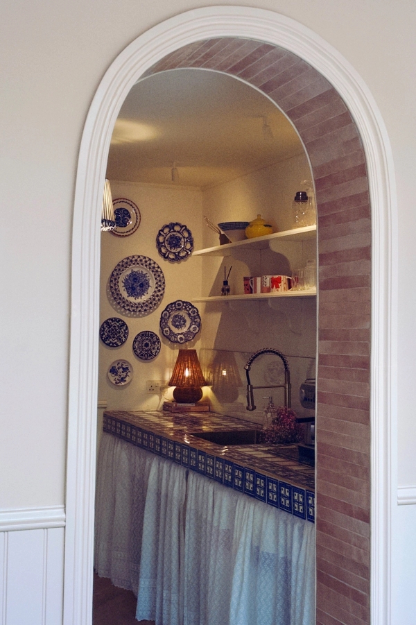 Classic archway frame revealing a vintage blue-and-white patterned tiled kitchen sink workspace, ideal for boutique interior editorial shoots, Love Locations.