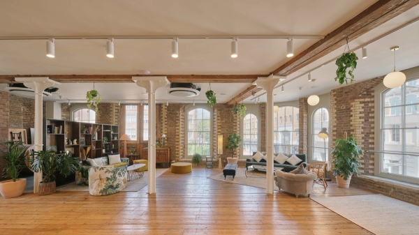 Wide view of The Lounge SE1’s open-plan loft with wooden floors, exposed brick, beams, and mixed vintage furnishings.