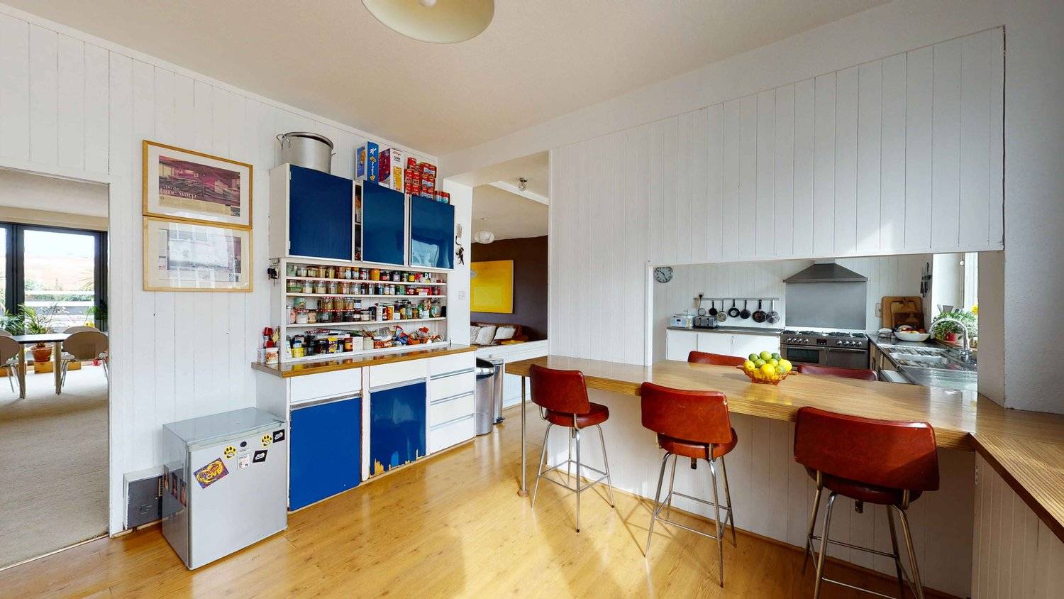 Authentic 1970s kitchen featuring blue and white cabinetry, breakfast bar with red stools, and wood-panelled ceiling, Love Locations SW16.