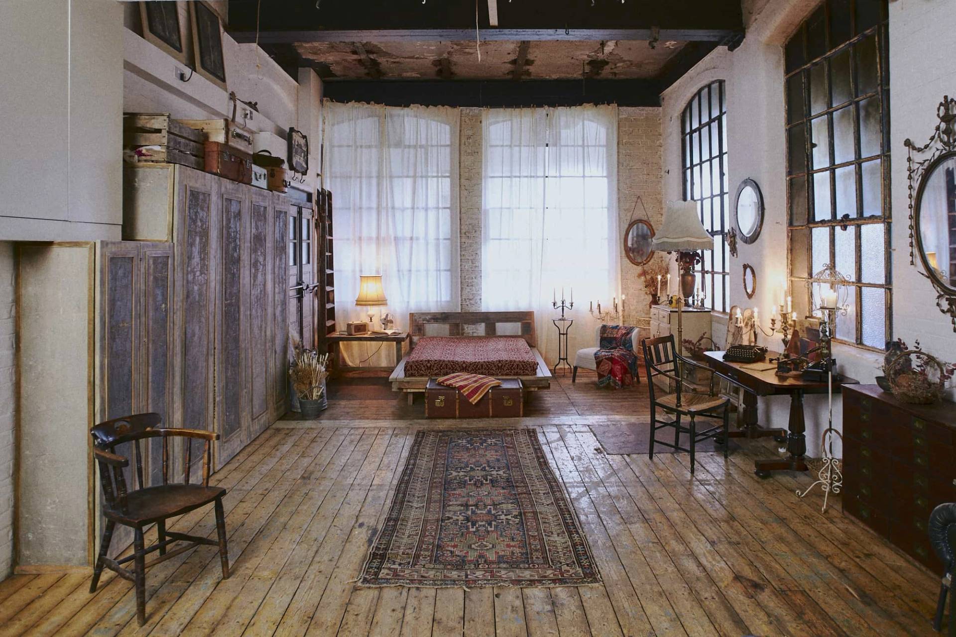 Spacious industrial bedroom set built inside an 1890s former dental factory warehouse featuring wooden flooring and a vintage rug, Love Locations.