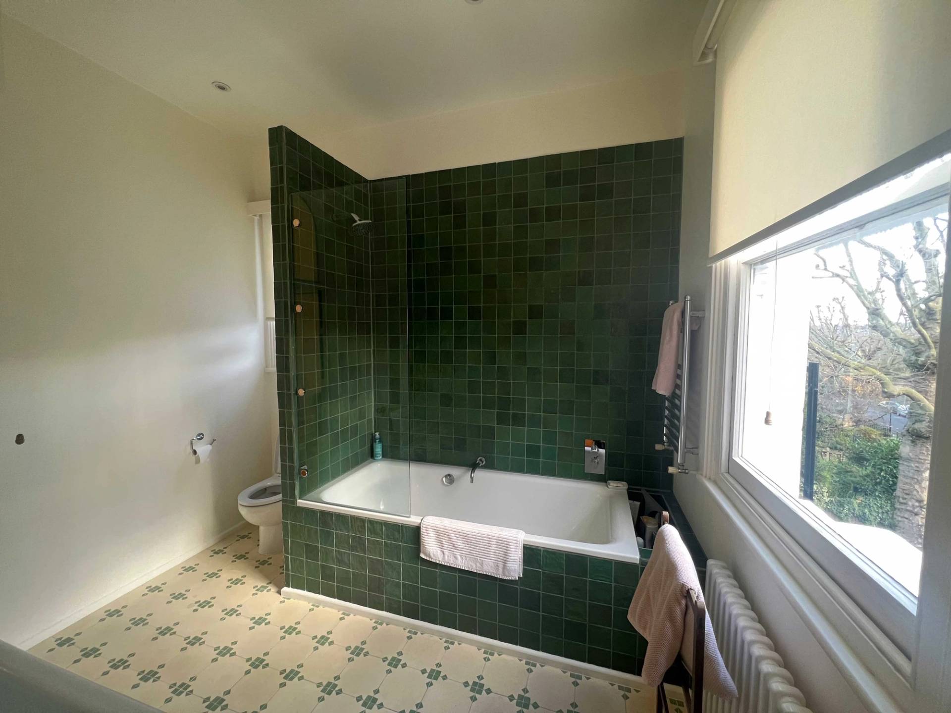 Deep forest green tiled shower and bathtub nook set on patterned tile flooring in Denmark Hill, Love Locations SE5.