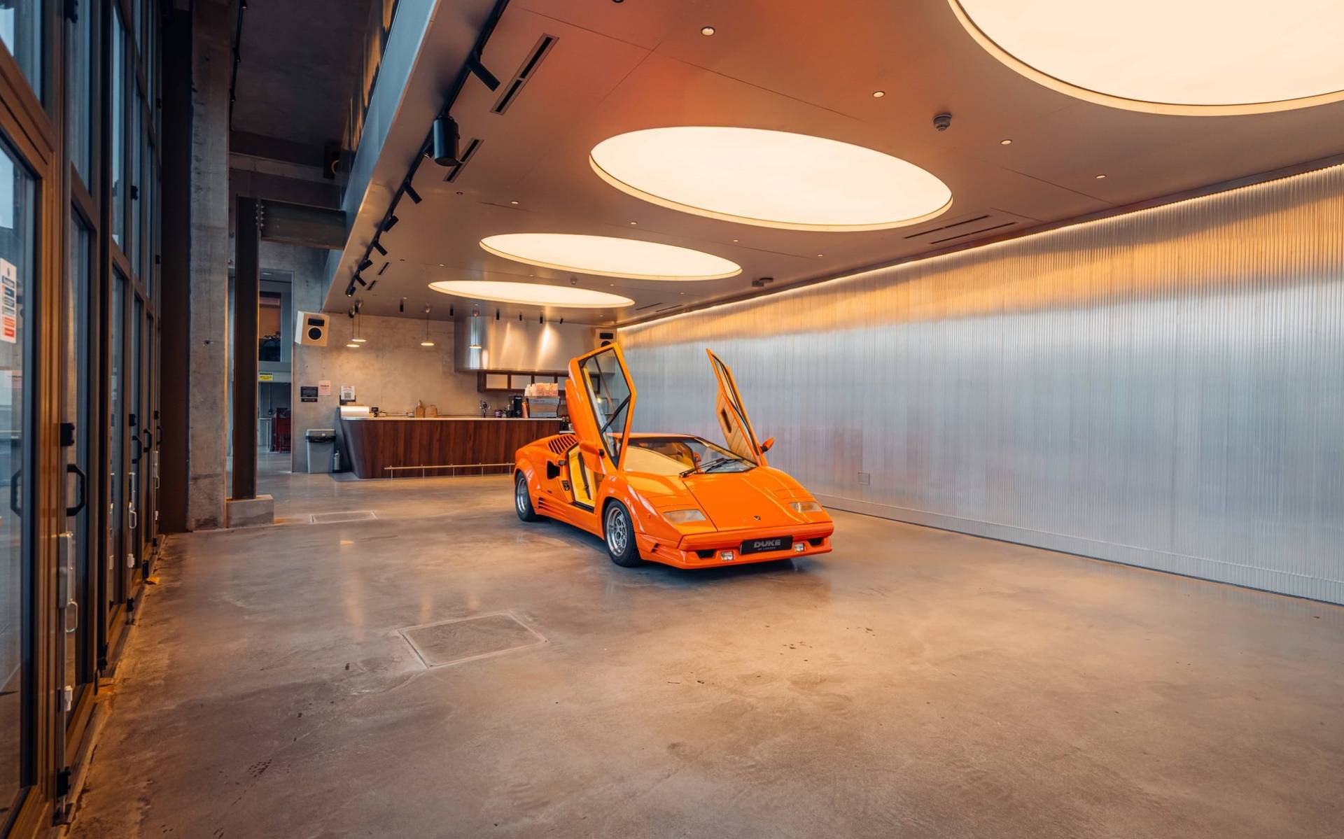 Wide view of an orange Lambo inside a modern industrial listening bar location house through Love Locations.