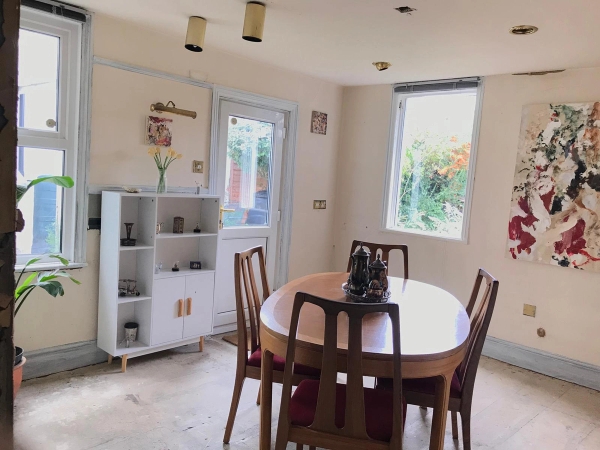 Casual dining space with an oval table setup, a freestanding cabinet unit, and a rear door leading out to the garden, ideal for indie music video scenes, Love Locations.