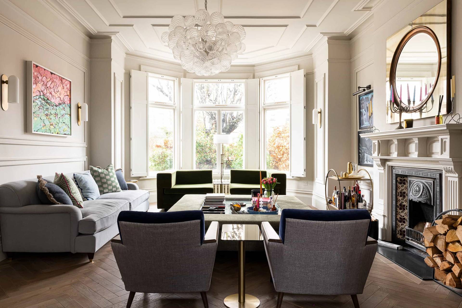 Victorian period reception room shoot location in Queens Park, NW6 featuring a bay window with shutters, plush velvet armchairs, and a bubble chandelier via Love Locations.